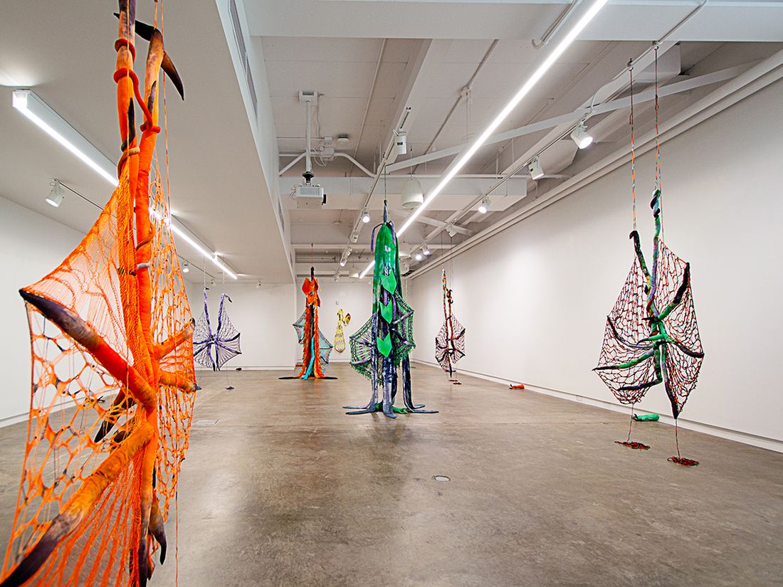 An installation shot of a show at Borzello Gallery. Installation of soft sculptures shaped most in large bat-like wings where the membranes are knitted with beads and hands with nails.