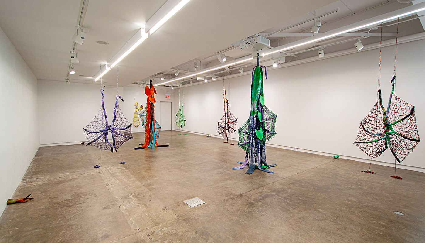 Installation of soft sculptures shaped most in large bat-like wings where the membranes are knitted with beads and hands with nails.
