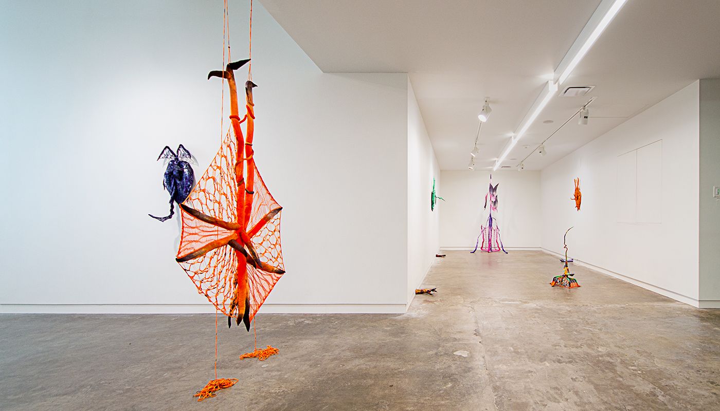 Installation of soft sculptures shaped most in large bat-like wings where the membranes are knitted with beads and hands with nails.