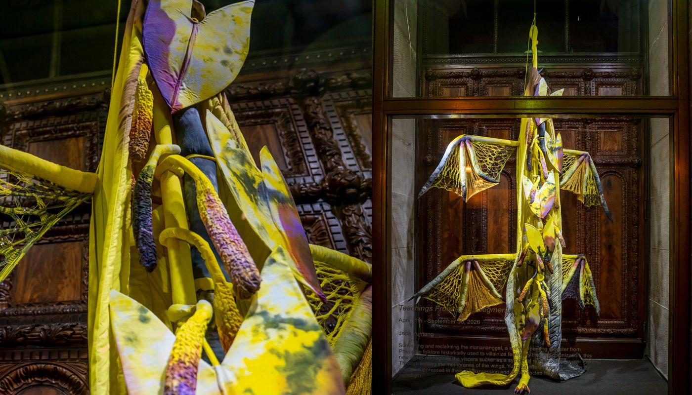 Installation of soft sculpture shaped primarily in yellow in large bat-like wings where the membranes are knitted with beads.