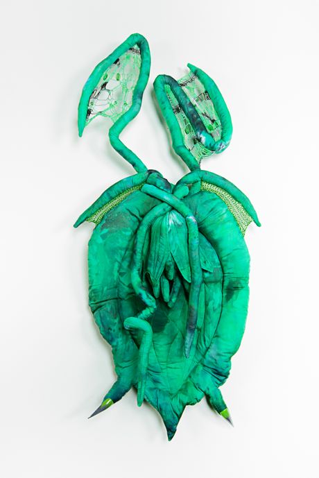 Hand dyed soft sculpture shaped like a budding plant with wings where the membranes are knitted with beads.