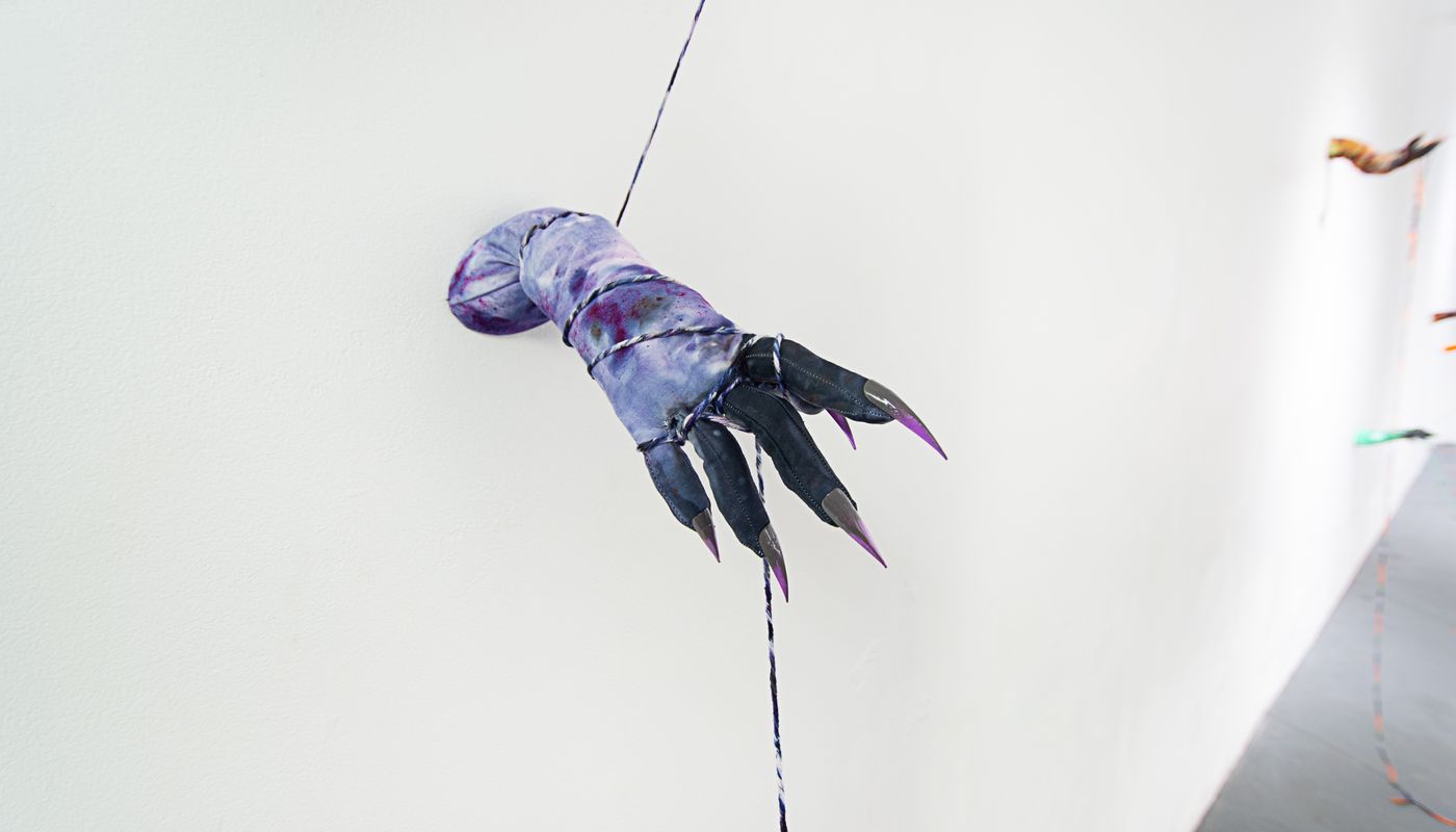 Installation of soft sculpture hands with nails on the wall, pulling rope.