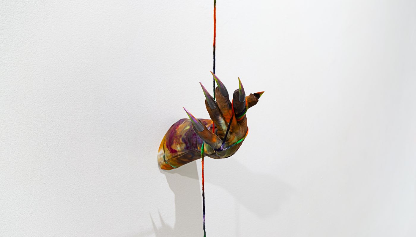 Installation of soft sculpture hands with nails on the wall, pulling rope.