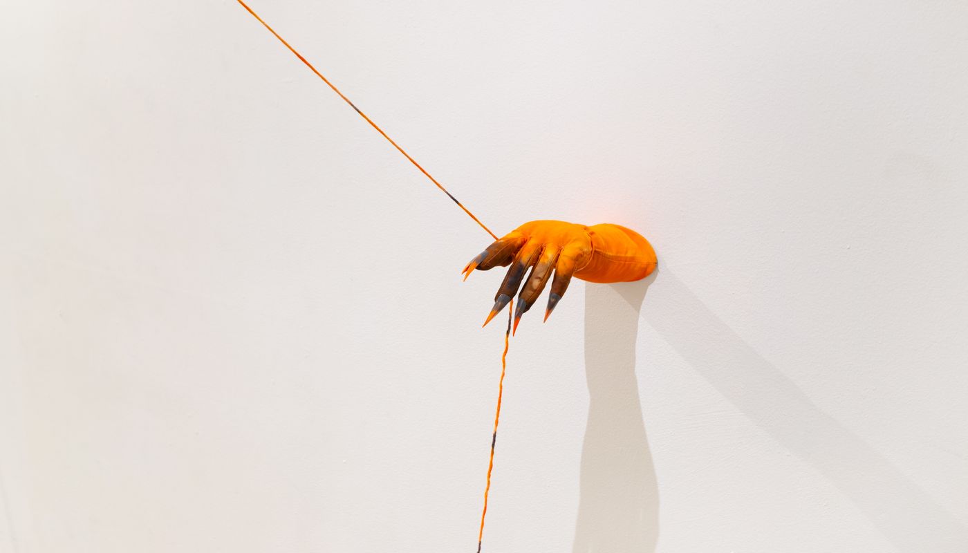 Installation of soft sculpture hands with nails on the wall, pulling rope.