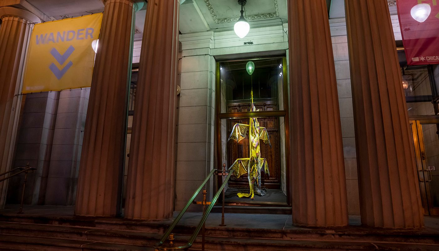 Installation of soft sculpture shaped primarily in yellow in large bat-like wings where the membranes are knitted with beads.