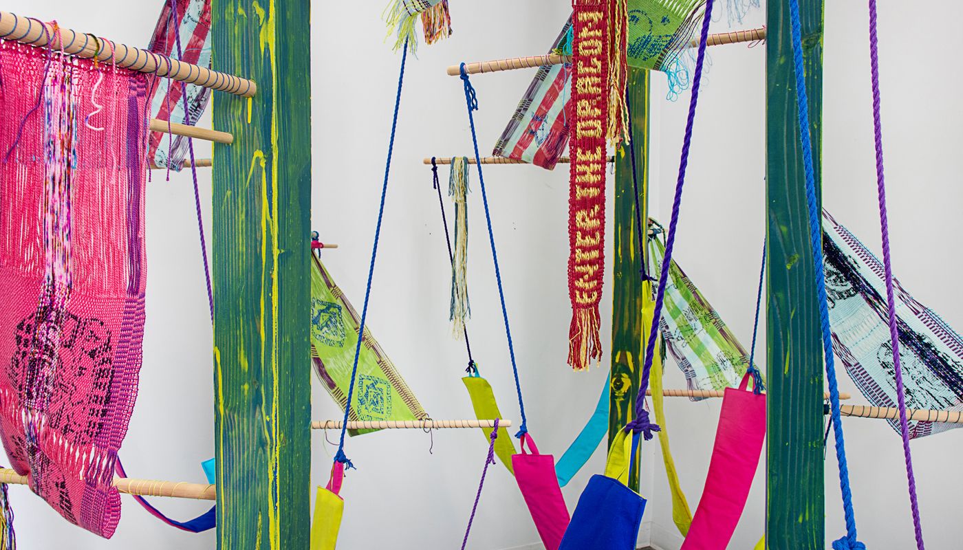 Colorful woven forms using backstrap weaving on posts installation.