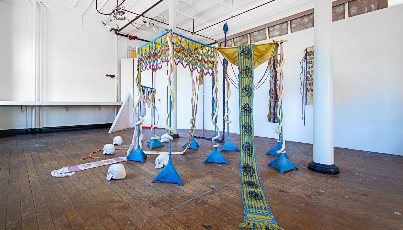 Colorful woven forms using backstrap weaving on fabric posts dyed with goldenrod, sappanwood, mulberry leaves, gardenia, annatto, logwood, and indigo.
