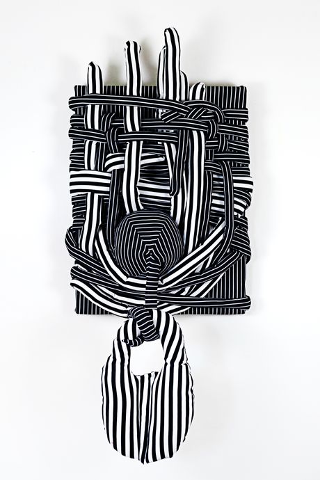 Wall sculpture in black and white stripes with soft sculpture elements.