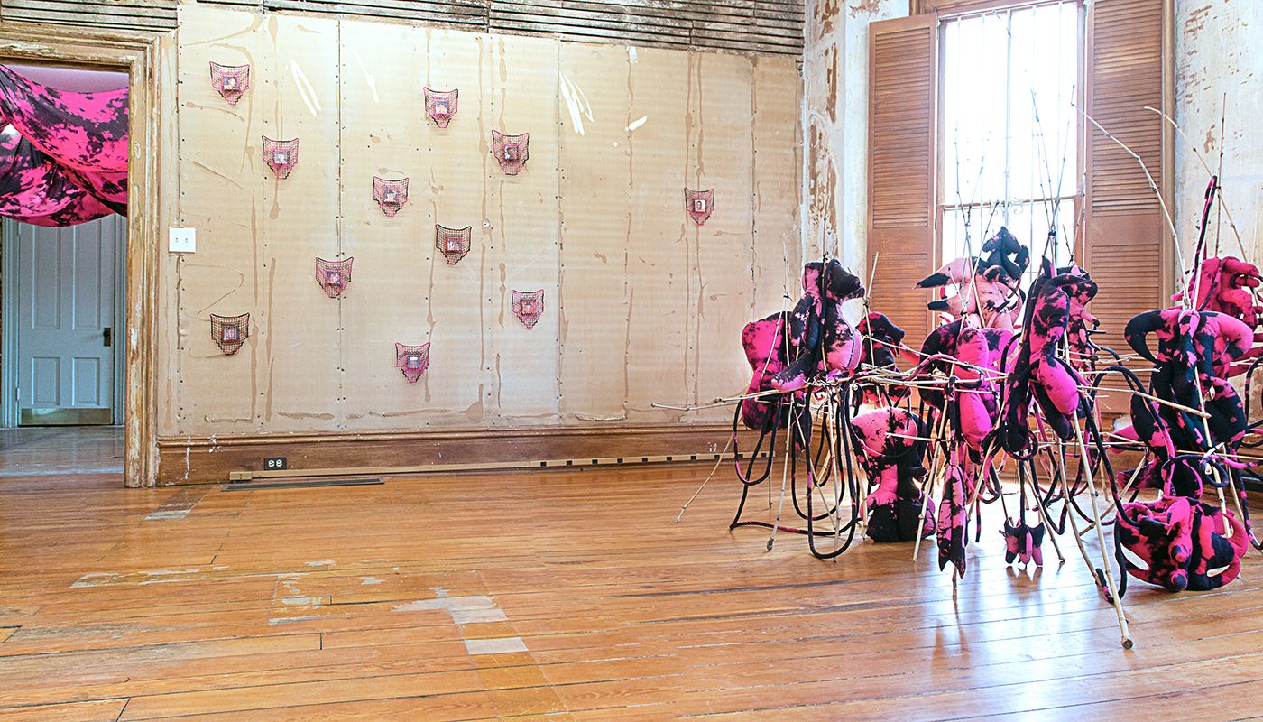 Installation of soft sculptures supported by bamboo structures with filet lace dyed in pink and black.