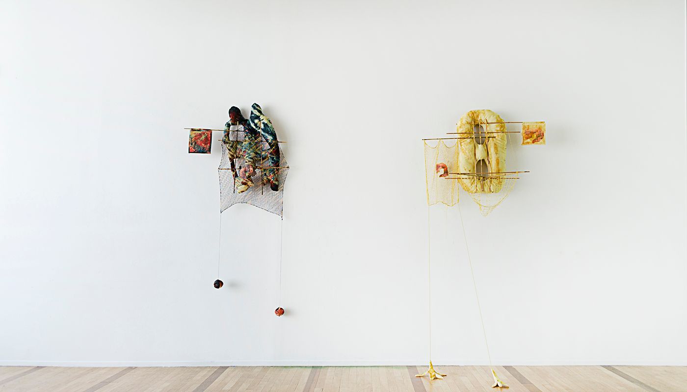 Installation shot taken in the Roger Brown Residency studio of two wall soft sculptures with filet lace and netting elements framed in bamboo that are tied using square lashing knots.