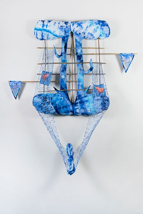 A wall soft sculpture tie dyed in hues of blues with filet lace and netting elements framed in bamboo that are tied using square lashing knots. Within the filet lace is an embedded gay pornographic image using a sublimation dye technique. The netting element is a long banner holding curved cylindrical soft sculpture.