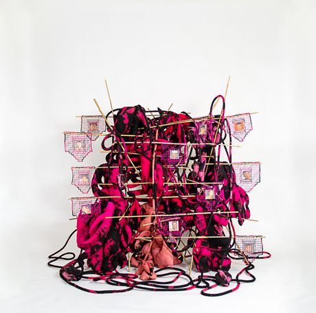 Free standing soft sculpture tie dyed in black and shades of pink with filet lace and netting elements supported in bamboo that are tied using square lashing knots. Within the filet lace is an embedded gay pornographic image using a sublimation dye technique.
